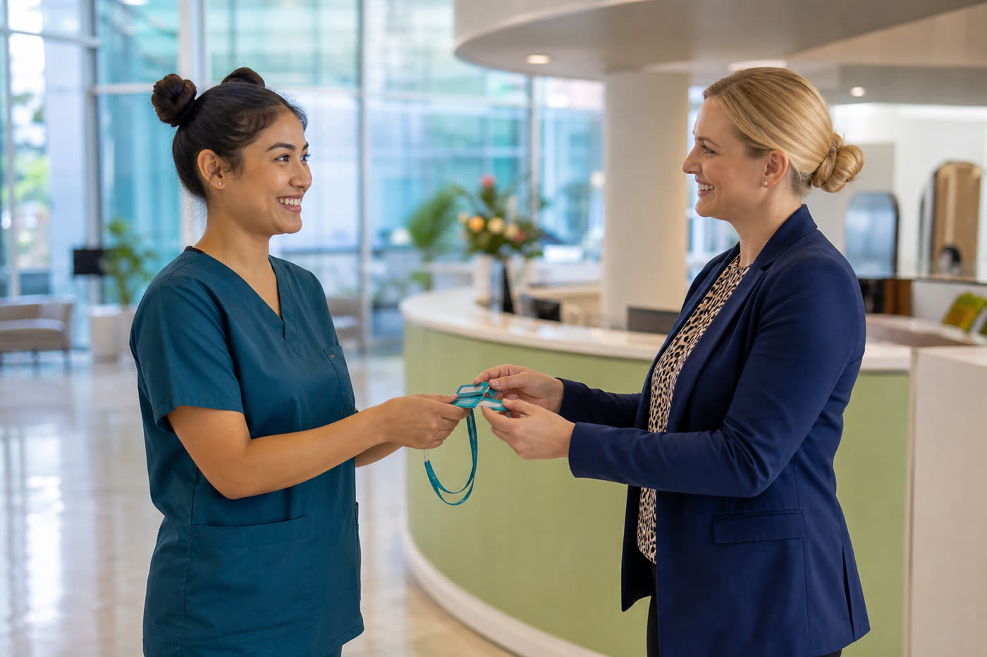 A recruitment consultant in a suit handing an ID badge to a new clinical starter at hospital reception