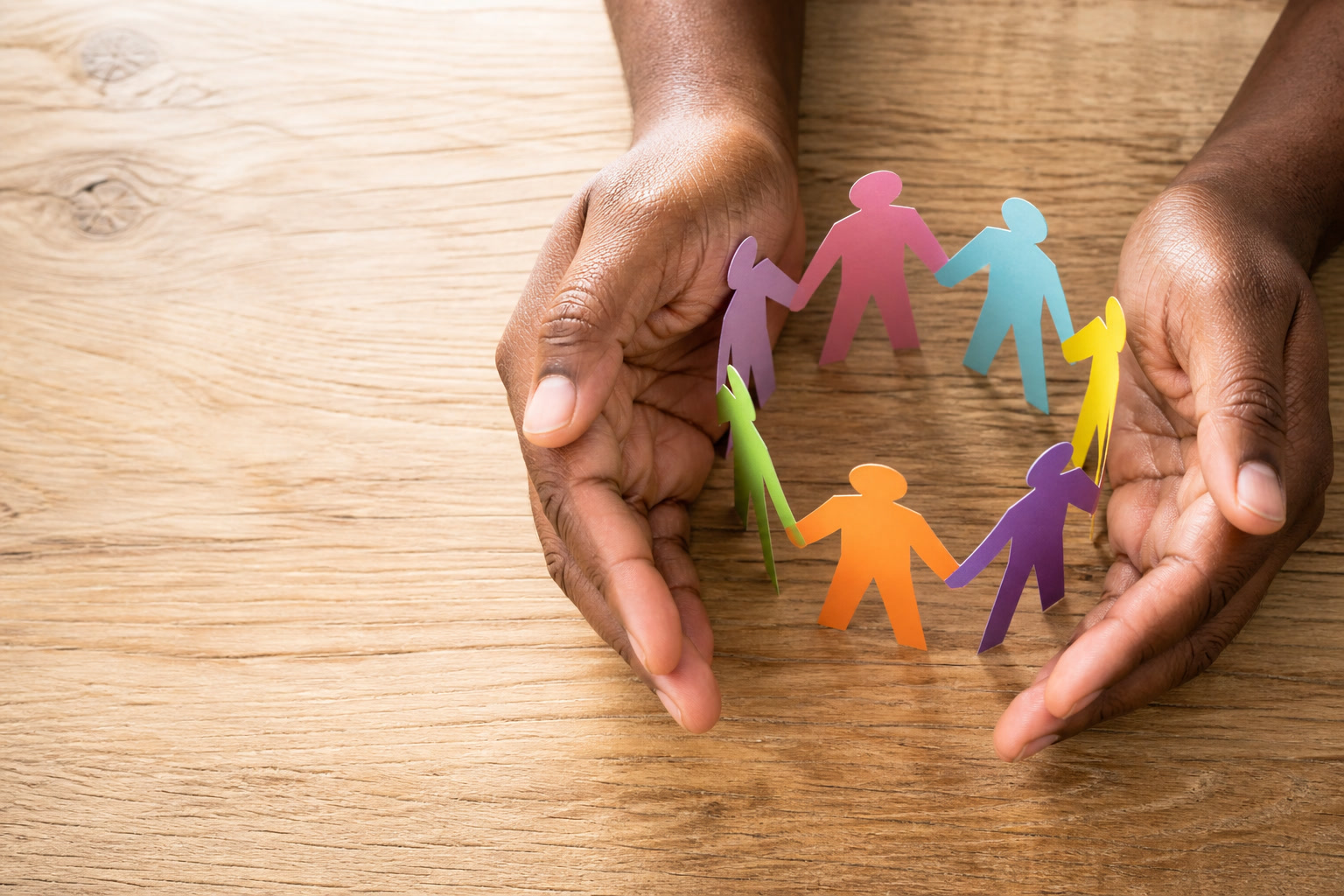Hands protecting a circle of diverse people — a symbol of safeguarding